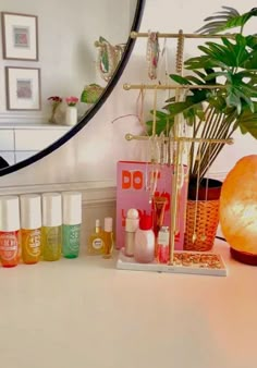 an assortment of beauty products sitting on a counter in front of a mirror and potted plant