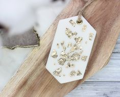 a white tag with gold hearts on it sitting on top of a piece of wood