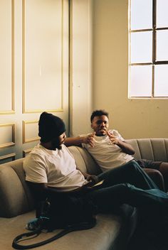 two men sitting on a couch talking to each other