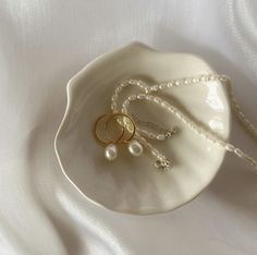 two wedding rings and pearls on a white plate