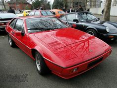 a red sports car parked next to other cars