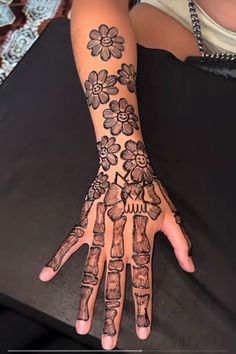 a woman's hand with tattoos on it and flowers painted on the palm area