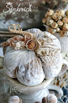 some white pumpkins are stacked on top of each other with flowers in the background