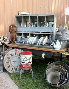 there are many old metal items on the grass near a table with plates and pans