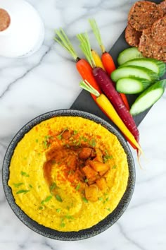 hummus in a bowl with carrots, celery and crackers on the side