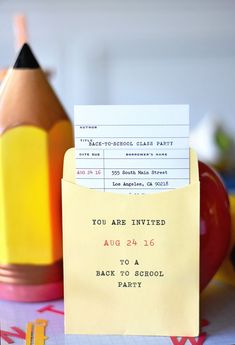 a yellow envelope with a note attached to it sitting on top of a table next to some school supplies