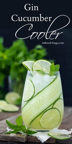 a glass filled with cucumber and limeade on top of a wooden table