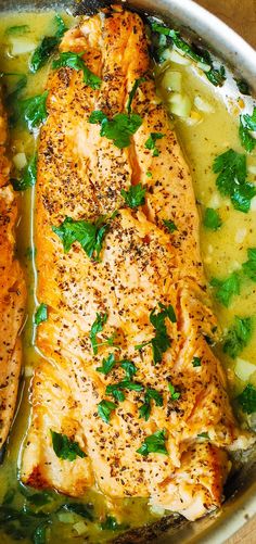 two fish fillets in a pan with broth and parsley on the side