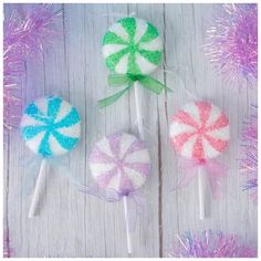 three lollipops are sitting next to each other on a white table with purple and green tinsel