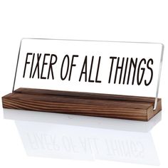 a desk sign that says fixer of all things on top of a wooden block