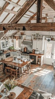 an open concept kitchen and dining area with wood flooring, white walls and exposed beams