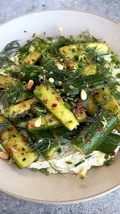 a white plate topped with cucumbers and other vegetables on top of a table