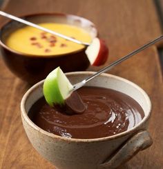 two bowls filled with chocolate pudding and an apple slice on top of one bowl next to the other