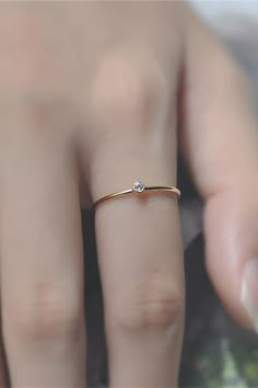 a woman's hand with a diamond ring on top of her finger and the other hand holding it