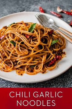 a white plate topped with spaghetti and sauce next to a fork on top of a table