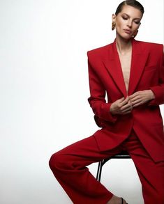 a woman in a red suit sitting on a chair