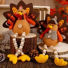 two stuffed turkeys sitting on top of a tree stump next to pine cones and other decorations