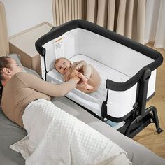 a woman laying in bed next to a baby with a crib on top of it