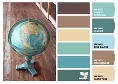 a globe sitting on top of a wooden floor in front of a window with color swatches