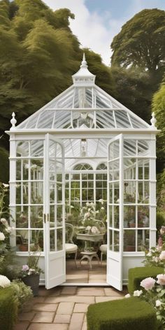 a white glass house surrounded by flowers and greenery