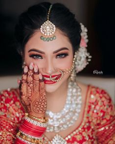 a woman in a red and gold bridal outfit holding her hands to her face