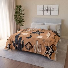 a bedroom with a bed covered in a brown blanket and cactus designs on it, next to a potted plant