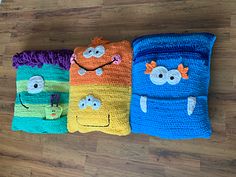 three crocheted pillows with faces on them sitting on the floor next to each other