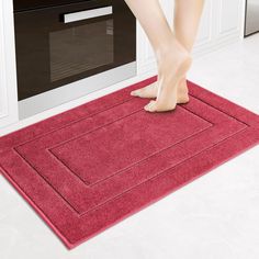 a person standing on a red rug in front of a stove top oven with their feet sticking out