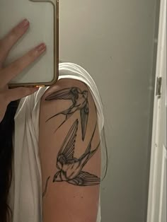 a woman with a bird tattoo on her arm holding up a cell phone to the camera