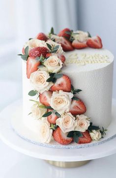 a white cake with strawberries and roses on top