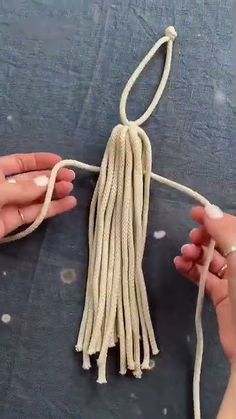 two hands are holding a string with white yarn on it