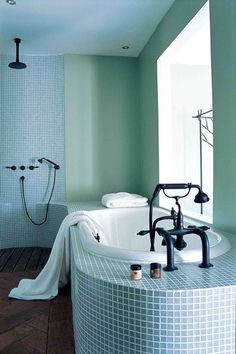 a bathroom with a large tub and shower head in it's center, surrounded by tiled walls