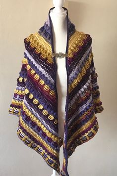 a white mannequin wearing a purple and yellow crocheted shawl