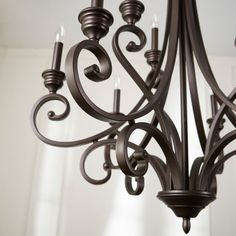 a chandelier hanging from the ceiling in a room with white walls and windows