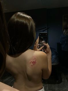 a woman is taking a selfie in the mirror with her tattoo on her back