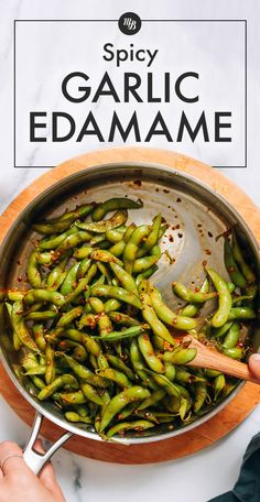 someone is cooking some green beans in a pan with the words spicy garlic edamame