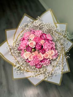 a bouquet of pink and white flowers on top of a table