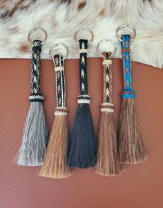 four tasseled keychains hanging on a leather wall with cowhide fur