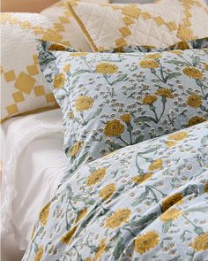 a bed topped with lots of yellow and white pillows