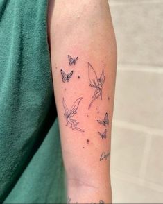 a woman's arm with tattoos on it and butterflies in the sky above her