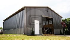 a large metal building sitting on top of a lush green field