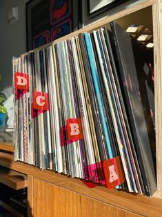 a collection of vinyl records sitting on top of a wooden shelf