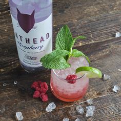 a raspberry and mint cocktail next to a bottle of cat head gin tonic