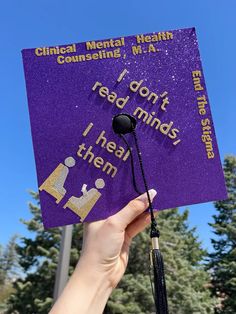 someone holding up a purple graduation cap that says i don't read minds, i hear them