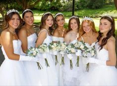 a group of bridesmaids in white dresses holding bouquets