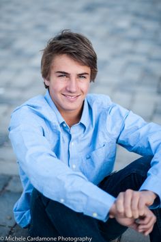 a man sitting on the ground with his arms crossed and looking at the camera smiling