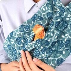 a person wearing a blue and white shirt holding a cell phone in their pocket with a small orange animal on it's lap