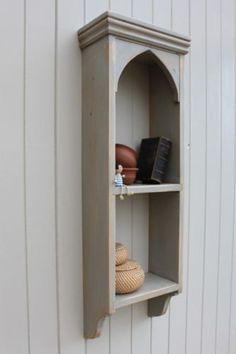 an old wooden shelf with some books and other items on it against a white wall