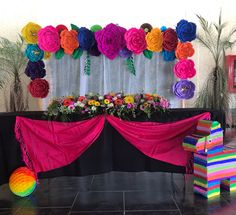 colorful flowers are on display in front of a black table with pink drapes and rainbow decorations