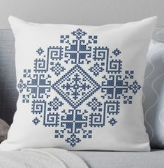 a blue and white cross stitch pillow on a couch